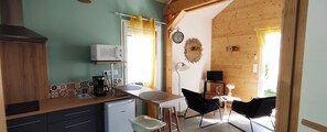 A kitchen with a microwave, coffee maker, and a refrigerator. There is a dining area with chairs and a table. - Lovely, cosy little chalet close to a wood (MONTARDON)
