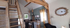 A modern kitchen with a wooden staircase, a dining area with bar stools, and a large mirror on the wall. - Lovely, cosy little chalet close to a wood (MONTARDON)