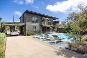 Enjoy a relaxing stay in this two-story house with a spacious backyard, featuring a covered driveway, swimming pool, and balcony with large windows.