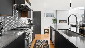 Una cocina moderna con una isla central, armarios oscuros y un salpicadero geométrico.