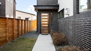 Un edificio moderno con puerta de madera, pared de ladrillo y camino de hormigón.