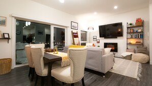 Una sala de estar moderna con comedor, chimenea y televisor montado en la pared.