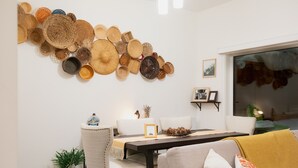 Un comedor con una colección de cestas colgantes en la pared, una mesa de comedor con un marco de fotos y un sofá con una manta.