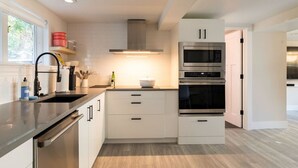 A modern kitchen with stainless steel appliances, white cabinetry, and a wooden floor. - Basement at 126 · Modern 1bedroom basement apartment newly remodeled (Kirkland)