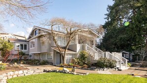 A two-story house with a front porch, a stone pathway, and a well-maintained lawn. - Basement at 126 · Modern 1bedroom basement apartment newly remodeled (Kirkland)