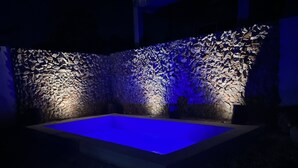 A swimming pool with a textured stone wall and blue lighting. - Casa Puerta del Sol ☀️Cozy 2bedroom Wifi. AC and TV (Mérida)
