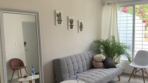 A modern living room with a grey sofa, a round coffee table, a large mirror, and three framed cactus artworks on the wall. - Casa Puerta del Sol ☀️Cozy 2bedroom Wifi. AC and TV (Mérida)