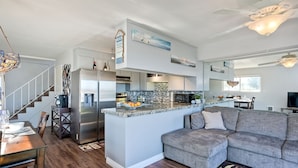 A modern kitchen with a central island, stainless steel appliances, and a dining area with a wooden table and chairs. - *NEW*Fantastic Location! Large Balcony Overlooking Yacht Club. Walk to Hotel Del (Coronado)