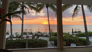 Vista de una playa con palmeras y un atardecer sobre el océano.