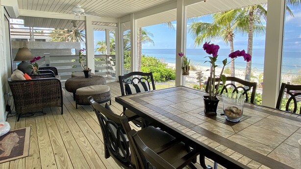 Un espacio de comedor al aire libre con techo y vistas a la playa y al océano.
