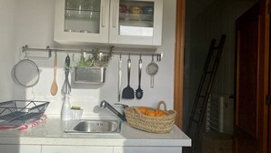 A kitchen with white cabinets, a stainless steel sink, and various utensils hanging on the wall. - Studio in a private estate in the center of the island (Sant Llorenç)