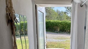 A hallway leading to a glass door with a view of a garden. There are two vases with dried plants on the floor. - Studio in a private estate in the center of the island (Sant Llorenç)