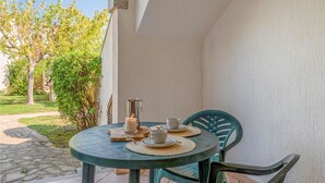 Eine kleine Terrasse im Freien mit einem runden Tisch, zwei Stühlen, einer Kerze und einem Metallbehälter.