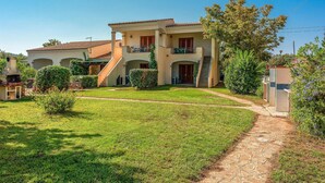 Ein zweistöckiges Haus mit überdachter Terrasse und gepflegtem Rasen.