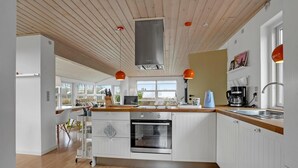 A modern kitchen with white cabinetry, a wooden ceiling, and a large window providing natural light. - 3 bedroom awesome home in Egernsund (Egernsund)