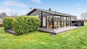 A modern house with a glass conservatory, a patio with outdoor furniture, and a well-maintained lawn. - 3 bedroom awesome home in Egernsund (Egernsund)