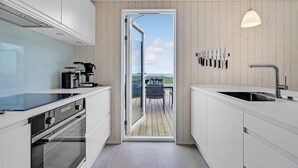 A modern kitchen with white cabinetry, a coffee machine, and a view of the outdoors through a glass door. - Nice home in Kalundborg with WiFi (Kalundborg)