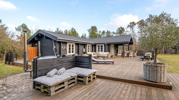 Eine Hütte mit einer Terrasse, Sitzgelegenheiten im Freien und einer Pergola.
