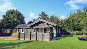 Eine rustikale Holzhütte mit geneigtem Dach, einer Veranda und einer kleinen Terrassenfläche.