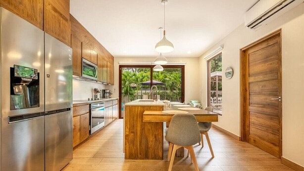 A modern kitchen with wooden cabinets, stainless steel appliances, and a central island with seating. - 3 King Suites | Pool, Outdoor Oasis | Casa Coralis (Potrero)