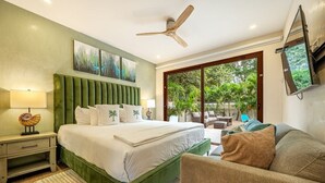 A bedroom with a large bed, a green headboard, a ceiling fan, and a view of a garden through a sliding glass door. - 3 King Suites | Pool, Outdoor Oasis | Casa Coralis (Potrero)