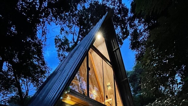 A modern, triangular-shaped building with a wooden exterior and large windows. - DECK1920 (Cascavel)