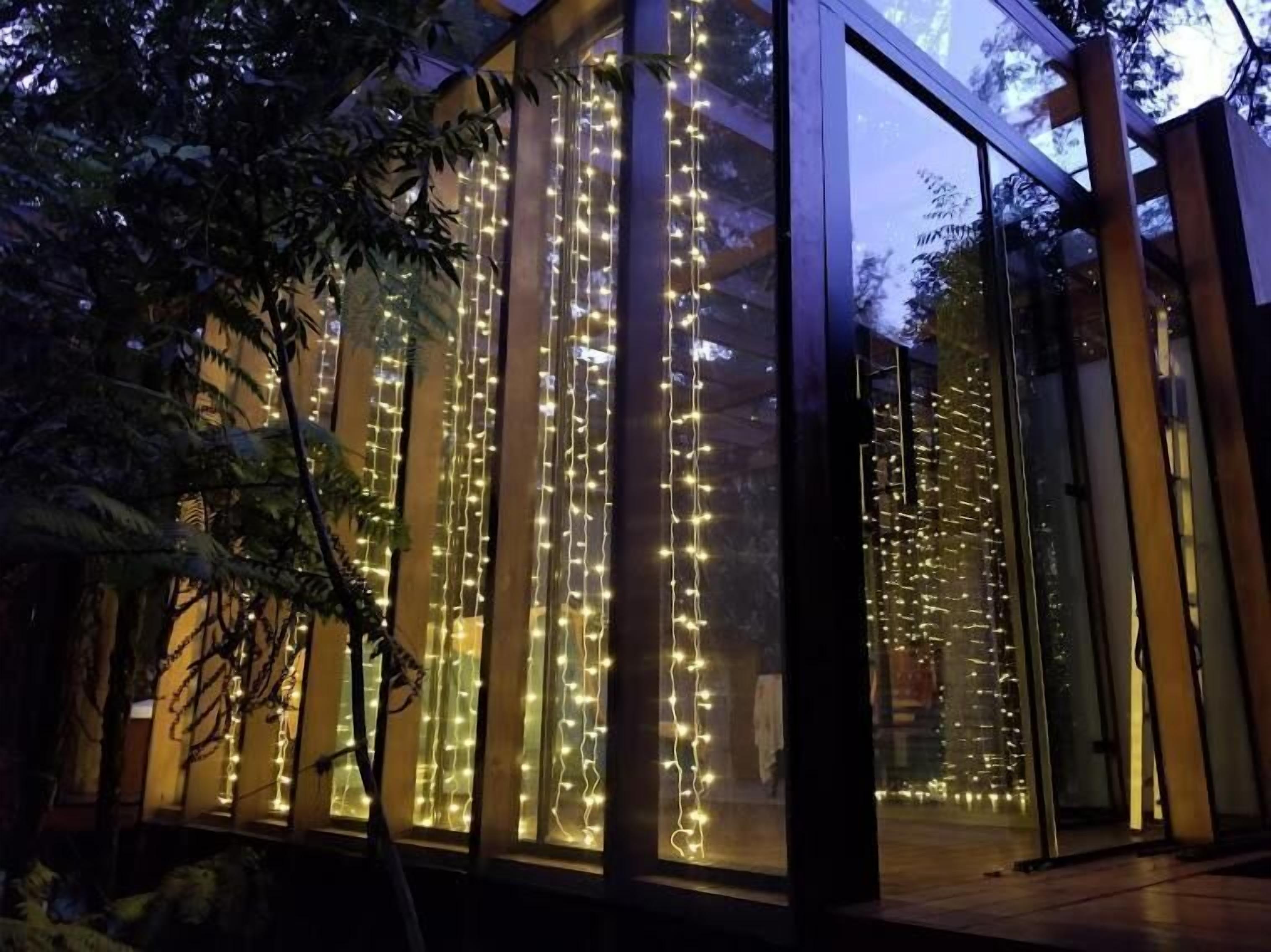 Un edificio moderno con amplios ventanales y luces verticales tipo guirnalda.