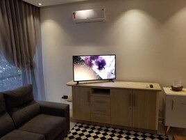 Una sala de estar moderna con un televisor de pantalla plana sobre un mueble de madera, un sofá gris y un suelo a cuadros.