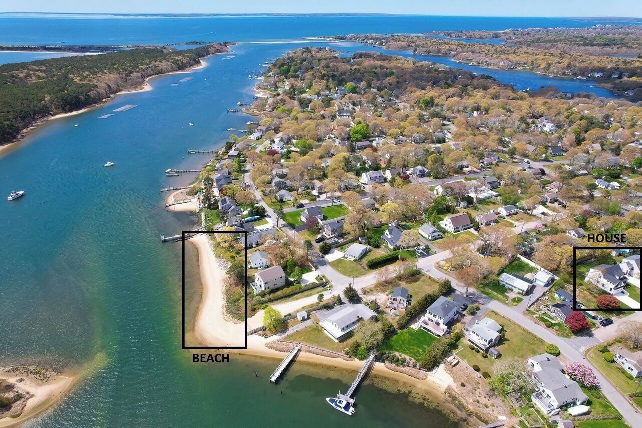 Vue aérienne d’une zone résidentielle côtière avec une plage, des maisons et un quai.