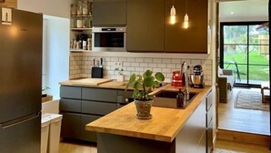 Eine moderne Küche mit einer zentralen Kochinsel, dunklen Schränken, einer Mikrowelle und einem Kühlschrank.
