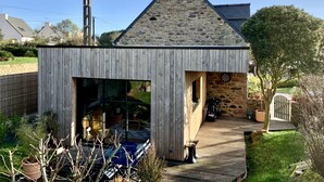 Ein Gebäude mit steinbedecktem Dach und Holzfassade, mit einem sichtbaren Dartspiel und einem gepflasterten Weg zum Eingang.