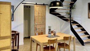 Ein Essbereich mit Holztisch und -stühlen, einer schwarzen Wendeltreppe und einer modernen Pendelleuchte.