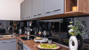 Cozinha moderna com armários cinza, bancada de madeira, forno embutido e uma janela grande.