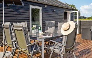 An outdoor dining area with a table and chairs, a bottle of wine, and a hat on the table. - Awesome home in Toftlund with WiFi (Toftlund)