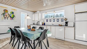 A modern kitchen with white cabinets, a dining table with chairs, and a window with a view of trees. - Awesome home in Toftlund with WiFi (Toftlund)