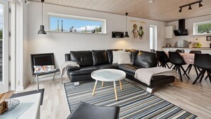 A modern living room with a black leather sofa, a round coffee table, and a striped rug. There is a dining area with black chairs and a small table. - Awesome home in Toftlund with WiFi (Toftlund)