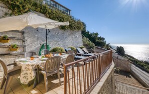 An outdoor dining area with a table set for two, overlooking a coastal view. - 2 bedroom awesome home in Cipressa (Cipressa)