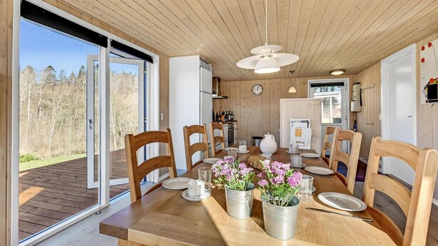 Un espace repas comprenant une table en bois, des chaises et une vue sur l’extérieur.