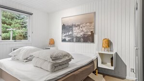 Makuuhuoneessa on sänky, ikkuna, seinälle ripustettu taulu ja yöpöytä, jossa on lamppu.
