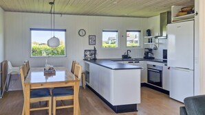 A modern kitchen with a central island, wooden dining table, and chairs. - Beautiful home in Glesborg with kitchen (Glesborg)