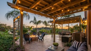 Eine Außenpatio mit einer Pergola, Sitzgelegenheiten und einem Feuerkorb.