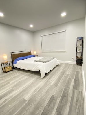 Quarto moderno com cama, luminárias de cabeceira, uma janela e estante.