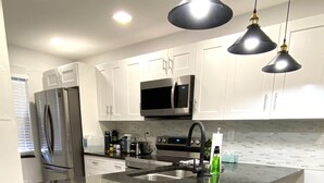 A modern kitchen with a large island, stainless steel appliances, and bar stools. - FL Beach Get-Away! 1BD/1BA in 2BD/2BA Available in South Florida (Delray Beach)