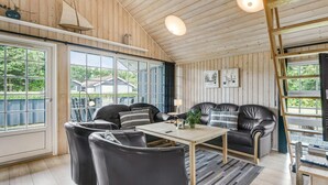 A cozy living room with a wooden ceiling, large windows, and a black leather sofa set. - Gorgeous home in Hemmet with sauna (Hemmet)
