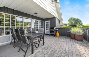 Une terrasse avec une table et des chaises, un barbecue et des plantes en pot.