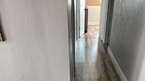 Un pasillo con piso de madera y paredes blancas.