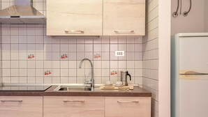 Une cuisine avec des meubles de couleur bois clair, un évier en acier inoxydable et un réfrigérateur blanc.