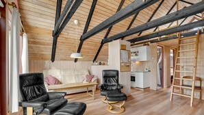 A cozy room with a wooden ceiling, a sofa, two black leather chairs, a small table, and a ladder. - Stunning home in Roslev with WiFi (Roslev)