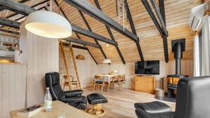 A cozy loft-style room with a wooden ceiling, a dining area, a fireplace, and a TV. - Stunning home in Roslev with WiFi (Roslev)