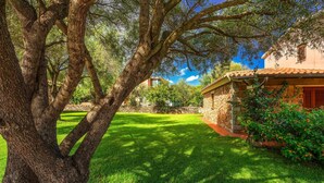 A stone building with a tiled roof, surrounded by a well-maintained lawn and trees. - Beautiful apartment in San Teodoro (San Teodoro)